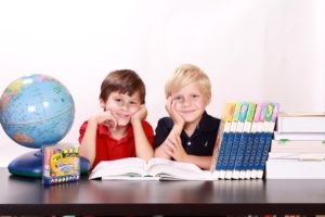 two boys with books and markers and a globe
